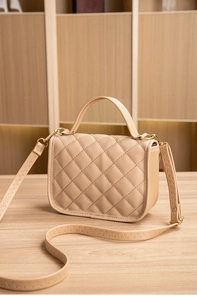Detail of beige quilted leather handbag featuring classic diamond stitching and gold hardware