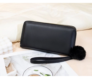 Détail du portefeuille long matelassé noir avec dragonne et pompon décoratif en peluche