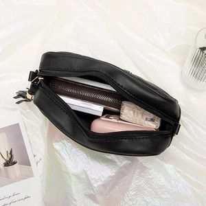 Black quilted crossbody bag with zip closure showing interior capacity and golden tassels