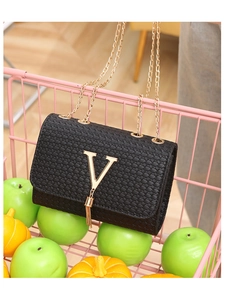 Detail of black woven texture bag with gold V-logo fringe in a pink shopping basket