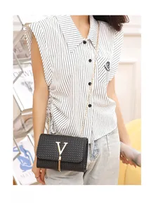 Detail of black woven shoulder bag with gold V logo, tassel charm and chain strap