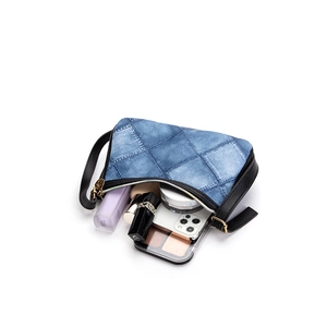 Blue denim shoulder bag for women showing spacious interior storage with makeup items