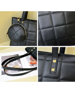 Detail view of black quilted tote bag set with gold hardware and small round coin purse