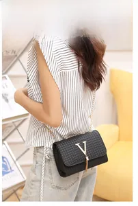 Detail of black woven texture bag with gold V-buckle tassel and metal chain strap