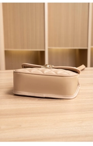 Detailed side and bottom view of beige quilted handbag with reinforced leather edges