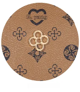 Close-up of golden floral metal clasp on brown monogram leather bucket bag with texture