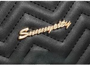 Macro view of wave-quilted black leather camera bag with golden metal logo detail