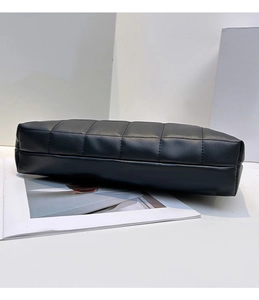 Détail de la texture en cuir noir matelassé et coutures fines sur la petite pochette carrée