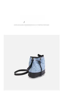 Detail der hellblauen Denim-Beuteltasche mit Blumenmuster und schwarzem Lederbesatz