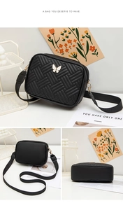 Détails du sac bandoulière noir tressé avec papillon métallique et large bandoulière