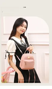 Dettaglio mini zaino rosa con fiocchi di nastro neri e placca in metallo dorato