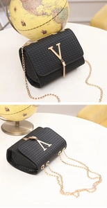 Close-up of black woven chain bag with gold V-shaped metal logo and tassel detail