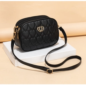 Detail of black crossbody bag with heart quilting, gold logo and dual zippers