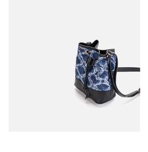 Detail der blauen Denim-Beuteltasche mit gestepptem Muster und schwarzen Lederakzenten