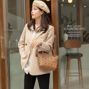 Vintage brown monogram bucket bag with leather handles shown by model in warm cafe setting