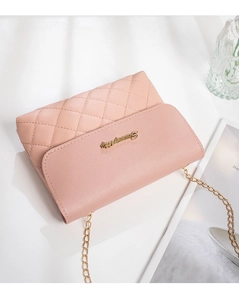 Detail of pink quilted crossbody bag with golden metal logo and elegant chain strap