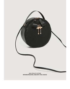 Close-up of black round crossbody bag featuring woven texture and golden swan pendant