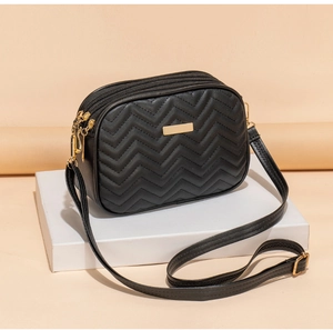 Detail of black zigzag quilted crossbody bag with triple zippers and gold hardware