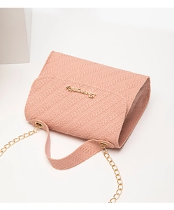 Détail de la texture tissée rose sur sac bandoulière avec logo en métal doré
