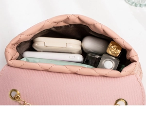 Detail shot of a pink quilted mini bag interior showing daily essentials and golden chain