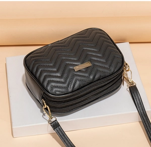 Detail of black crossbody bag featuring three zipper pockets and elegant wave stitching