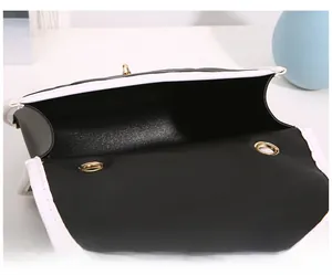 Close-up of black and white contrast leather bag with golden twist lock detail