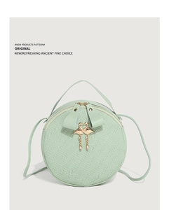 Detail of light green round crossbody bag with embossed texture and gold flamingo clasp