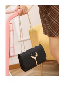 Detail of black woven shoulder bag featuring golden deer head clasp and metal tassels
