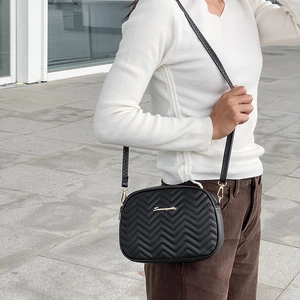 Women's black quilted wave pattern crossbody camera bag with adjustable strap and gold logo