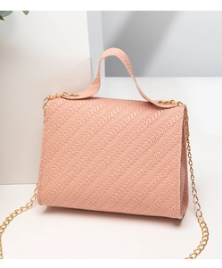 Détail de la texture tressée rose sur un petit sac carré avec bandoulière dorée