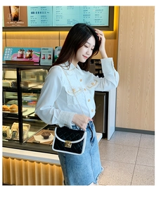 Chic black quilted crossbody bag with white contrast trim and gold buckle shown on model