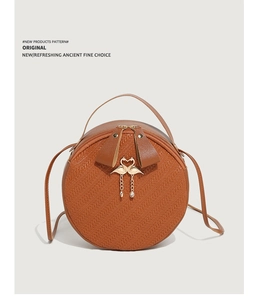Detail of round brown crossbody bag with heart-shaped flamingo buckle and pearl chain