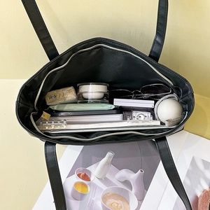 Black leather tote bag with spacious interior and internal zipper pocket for essentials