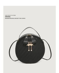 Detail of black round shoulder bag featuring dual flamingo charm and woven texture