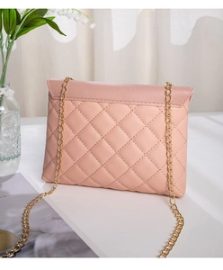 Detail shot of dusty pink quilted leather handbag with gold chain strap on table