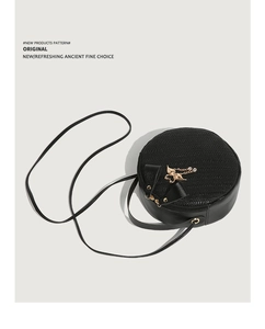 Macro view of woven texture on black round crossbody bag with golden swan pendant