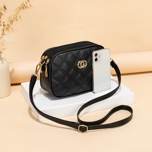 Quilted black leather crossbody bag with triple zippers and gold hardware on a display stand
