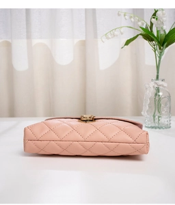 Detail of pink quilted chain bag featuring a gold twist lock and elegant rhombic stitching