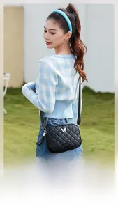 Detail of black quilted crossbody bag featuring metal butterfly buckle and tassel charm