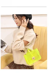 Fluorescent PVC mini bag with gold chain strap and metal lock shown on a yellow sofa