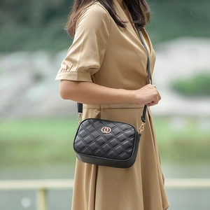 Classic black quilted leather crossbody bag with golden hardware shown on a model outdoors