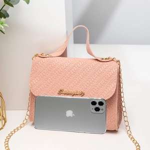 Sac à main rose à texture tissée avec bandoulière chaîne dorée et poignée sur fond blanc