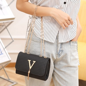 Women's black textured crossbody bag with gold V-logo and tassel on a chain strap