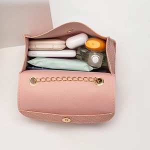 Petit sac bandoulière rose tissé avec chaîne dorée montrant l'espace de rangement interne