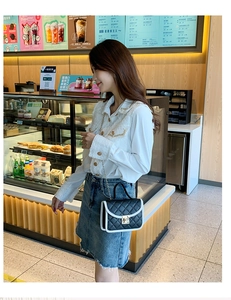 Chic black quilted crossbody bag with white trim and gold lock shown in a cafe setting