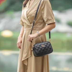 Chic black quilted crossbody bag with golden hardware shown on a female model outdoors