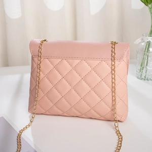 Sweet pink quilted small square crossbody bag with gold chain strap on white table