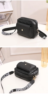 Détail d'un sac bandoulière matelassé noir avec boucles dorées et large sangle tissée