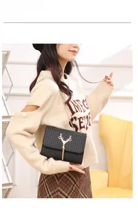 Detail of black woven leather shoulder bag with gold deer-shaped lock and tassel chain