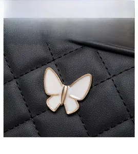 Close-up of black quilted leather bag with elegant white enamel butterfly metal decoration